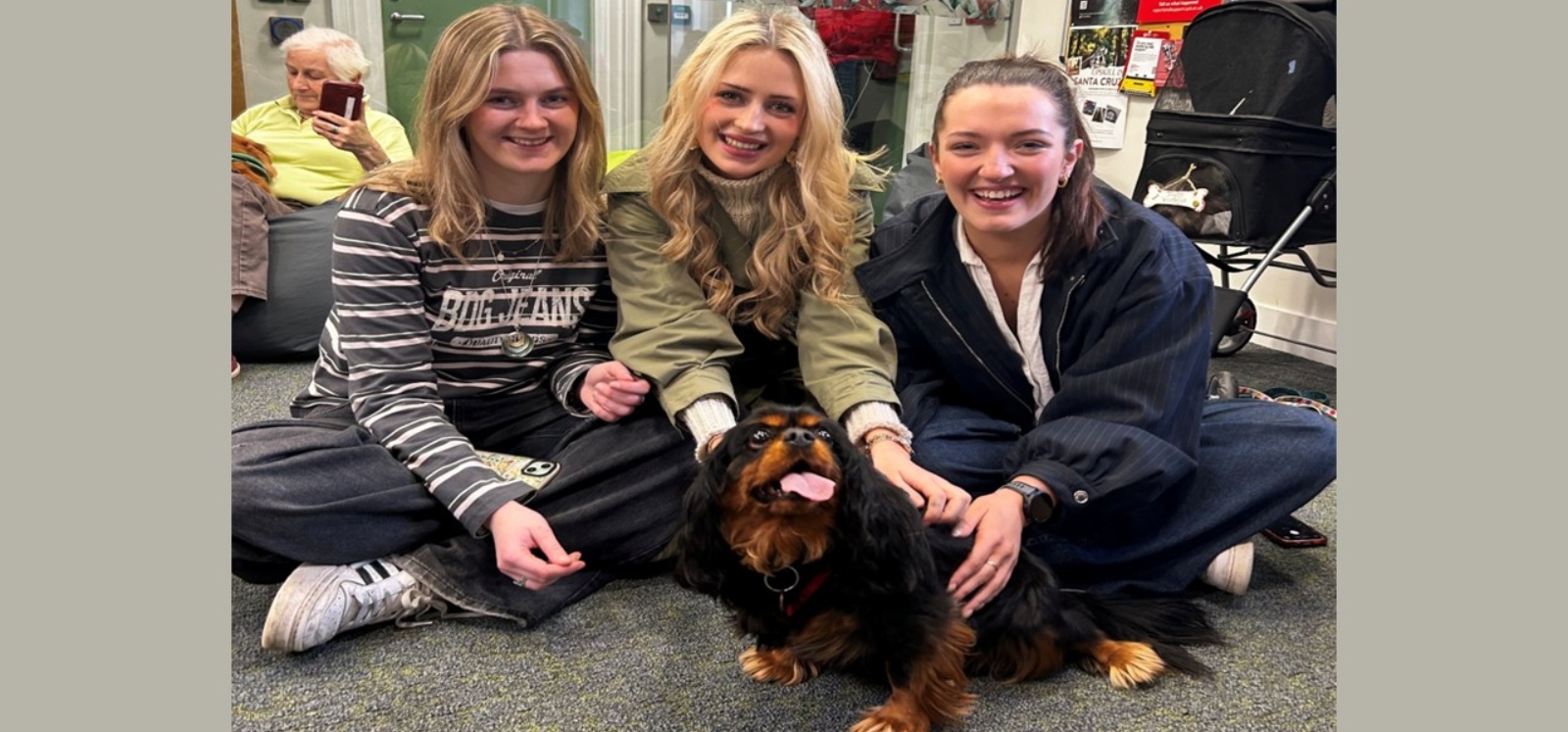 three students petting a black and brown dog